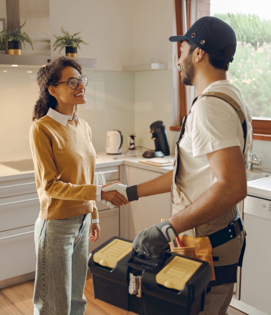 A handyman shaking hands with a woman in a kitchen. Home services digital marketing connected these two for a beneficial partnership.