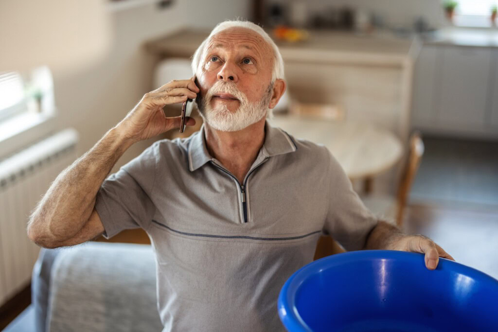 Elderly man calling plumber for water leakage at home.