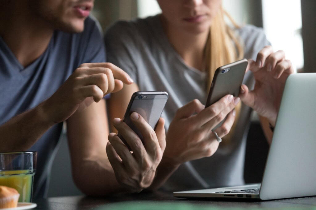 Close up view of man and woman using smartphones looking at mobile apps